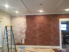 a brick wall being painted with white paint and a ladder in the foreground next to it