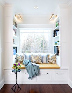 a window seat in the corner of a room with bookshelves on either side