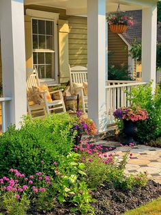 the front porch is decorated with flowers and rocking chairs for relaxing in the summer sun