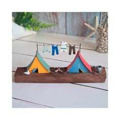 a wooden stand with clothes hanging from it's sides and a small tent on the other side