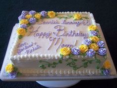 a birthday cake decorated with flowers and the words happy birthday mom on it's side