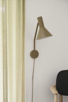 a lamp that is on the side of a wall next to a chair and window