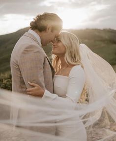 a bride and groom embracing each other in front of the sun