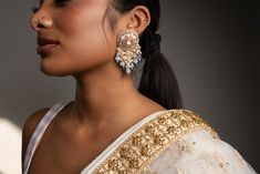 Dress up your outfits with our opulent Grey Nirvi Earrings. Handcrafted with high-quality Pachi Kundan, pearls and crystals on Gold plating, these earrings are a must-have in your jewelry box. Specifications Materials used: Pachi Kundan, pearls, crystals, Gold plating At Romikas, we pride ourselves on the craftsmanship and high quality of our jewelry, designed to enhance your natural beauty. Please contact us with any questions. Kundan Earrings, Gold Plating, Natural Beauty, Diamond Earrings, Jewelry Box, Crown Jewelry, Dress Up, Plating, Crystals