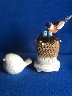 a small crocheted bird nest sitting on top of a white tea pot