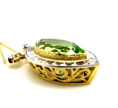 This beautiful, statement features an unusual, marquise shape peridot in a necklace that will never go out of style. The peridot is far less yellowish-green than most peridot; rather, it is a slightly "minty" green color. It is set in a yellow gold bezel and framed with a striking white gold border. Accented by four small, round white cut diamonds in the elaborately designed bail, this is a one-of-a-kind piece, handmade of 18k yellow and white gold by our Master Jewelers in Los Angeles. The leve Fine Jewelry Green Marquise Necklaces, Fine Jewelry Green Marquise Cut, Formal Green Marquise Jewelry, Green Marquise May Birthstone Jewelry, Green Marquise Jewelry For May Birthstone, Elegant Green Marquise Necklace, Green Marquise Cut Gemstone Jewelry, Elegant Green Marquise Cut Jewelry, Green Marquise Cut Jewelry For Gifts