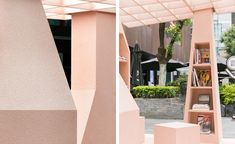 a pink book shelf sitting on the side of a road next to a tall building