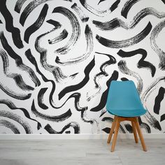 a blue chair sitting in front of a wall with black and white designs on it