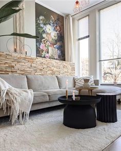 a living room filled with furniture and a large painting on the wall above it's windows