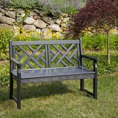 a wooden bench sitting on top of a green grass covered park field next to a stone wall