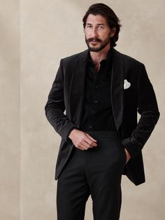 When the occasion calls for something truly special, reach for this velvet tuxedo blazer.  We selected a beautiful quality of cotton velvet for its construction, cutting the fabric pile-up to add to its luster.  Finally, we added a roped shoulder for a dressed up feel, and a traditional shawl collar cut in the very same velvet.  Tailored Slim Fit: More relaxed than our Slim Fit, this English cut style has a more structured shoulder construction.  Shawl lapel and one-button front.  Front and ches Unique Black Suits For Men, Velvet Suit Men Black, Men’s Gala Attire, Black Velvet Suit Mens, All Black Suits For Men, Black Winter Wedding Suit, Black Velvet Tuxedo Suit, Men Holiday Outfit, Elegant Long Sleeve Velvet Tuxedo