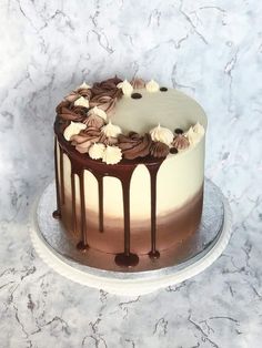 a chocolate cake with white frosting and flowers on top sitting on a marble table