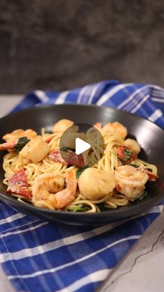 pasta with shrimp and spinach in a skillet on a blue checkered towel