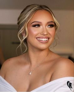 a woman with blonde hair wearing a white dress and diamond necklace smiling at the camera