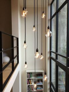 the light bulbs are hanging from the ceiling in the room with bookshelves and windows