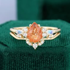 an orange and white diamond ring sitting on top of a green velvet cushioned box