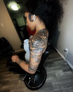 a woman sitting on top of a chair with a tattoo on her arm and shoulder