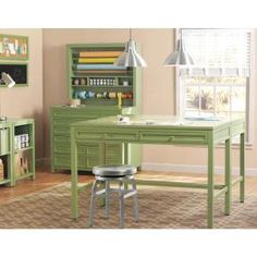 a green desk and chair in a room with lots of bookshelves on the wall