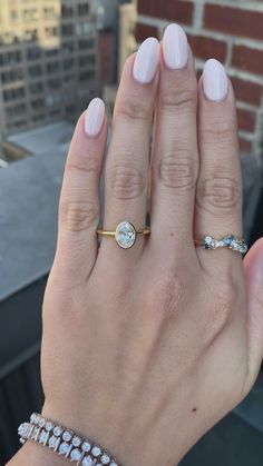 a woman's hand with three different rings on her fingers and two diamond bracelets