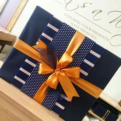 a gift wrapped in blue and gold with a bow on it sitting on a table