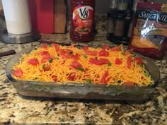 a casserole dish filled with cheese and peppers on top of a granite counter