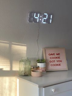 a clock that is sitting on top of a dresser next to a sign with the words'give me cookie got you cookie '