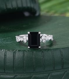 a black and white diamond ring sitting on top of a green surface