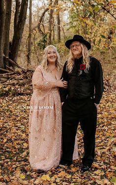 a man and woman dressed up in costume standing next to each other with leaves on the ground