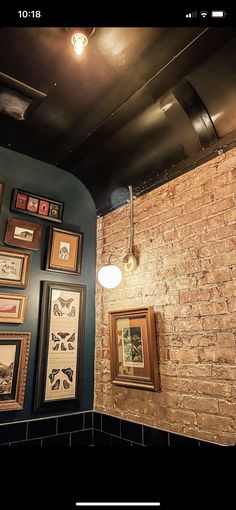 a brick wall with framed pictures on it and a light fixture hanging from the ceiling