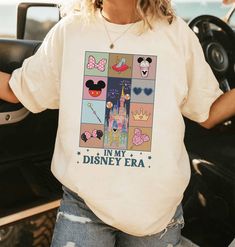 a woman standing next to a car wearing a white shirt with disney characters on it