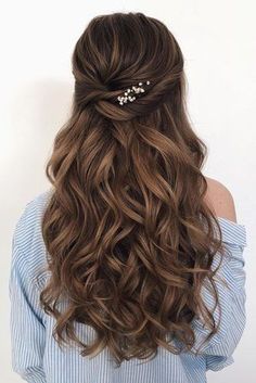 the back of a woman's head with long wavy hair and gold leaves on it