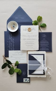 the wedding stationery is laid out on top of the blue and white envelopes