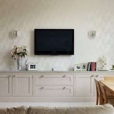 a flat screen tv mounted to the side of a wall above a dining room table