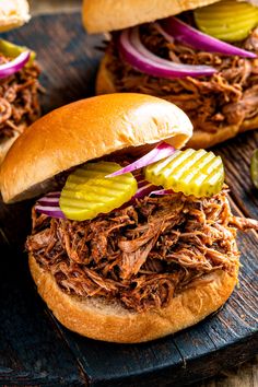 two pulled pork sandwiches with pickles and onions