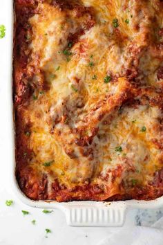 lasagna casserole in a white dish with parsley on the side