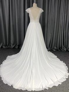 a white wedding dress on a mannequin in front of a curtained backdrop