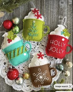 four christmas mugs on a doily with ornaments