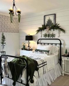 a bedroom with white walls and black iron bedspread, green throw pillows on the bed