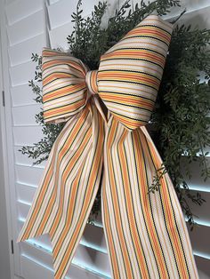 an orange and white striped bow hanging on the side of a window with shutters