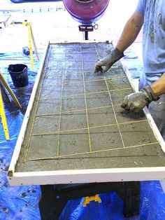 a man is working with cement on a table