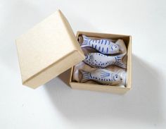 four fish figurines in a box on a white surface with the lid open