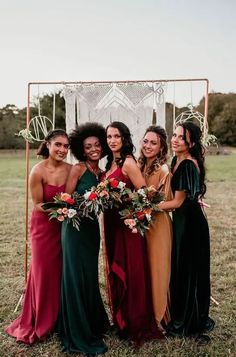 a group of women standing next to each other in front of a metal frame with flowers on it