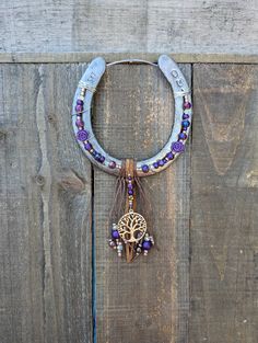 a necklace with beads and a tree on it hanging from a wooden wall next to a pair of scissors