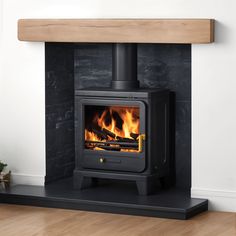 a wood burning stove in a room with white walls and wooden flooring on the side