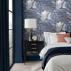 a bedroom with blue and white wallpaper, a black night stand, and a bed in front of a window