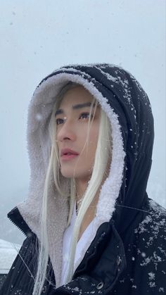 a woman with blonde hair wearing a black jacket and white hoodie in the snow