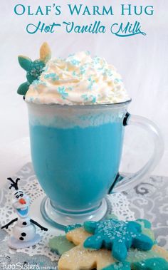 there is a blue drink with whipped cream in it and cookies on the table next to it