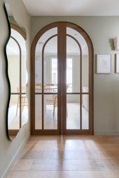 an arched wooden door in a home with hardwood floors