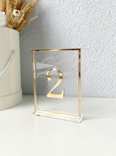 there is a gold number two on the table next to a vase with dried flowers