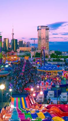 an aerial view of a carnival with rides, lights and people in the background at dusk